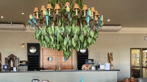 A modern kitchen with a central island, a round glass table, and a unique chandelier with bird-shaped lights. - Hotel OT (Tres Lagoas)
