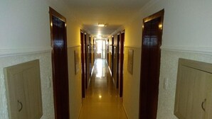 Un lungo e stretto corridoio con porte su entrambi i lati, che conduce a delle stanze.