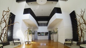 Un hall d’entrée spacieux avec un plafond haut, un plancher en bois et un mobilier moderne.
