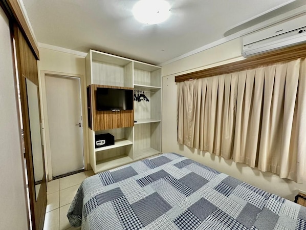 A bedroom with a bed, wardrobe, and an air conditioning unit.