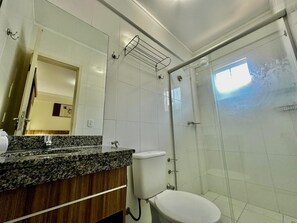 A bathroom with a granite countertop, a toilet, a glass shower enclosure, and a mirror. - Lacqua Di Roma I Via Caldas (Caldas Novas)