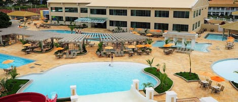 Un complexe hôtelier doté de plusieurs piscines, de chaises longues et de parasols.
