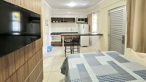 A compact kitchen with a microwave, refrigerator, and a dining area with chairs. - Lacqua Di Roma I Via Caldas (Caldas Novas)