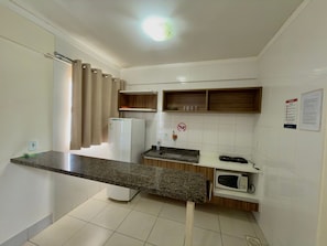 A small kitchenette with a refrigerator, microwave, sink, and wooden shelves. - Lacqua Di Roma I Via Caldas (Caldas Novas)