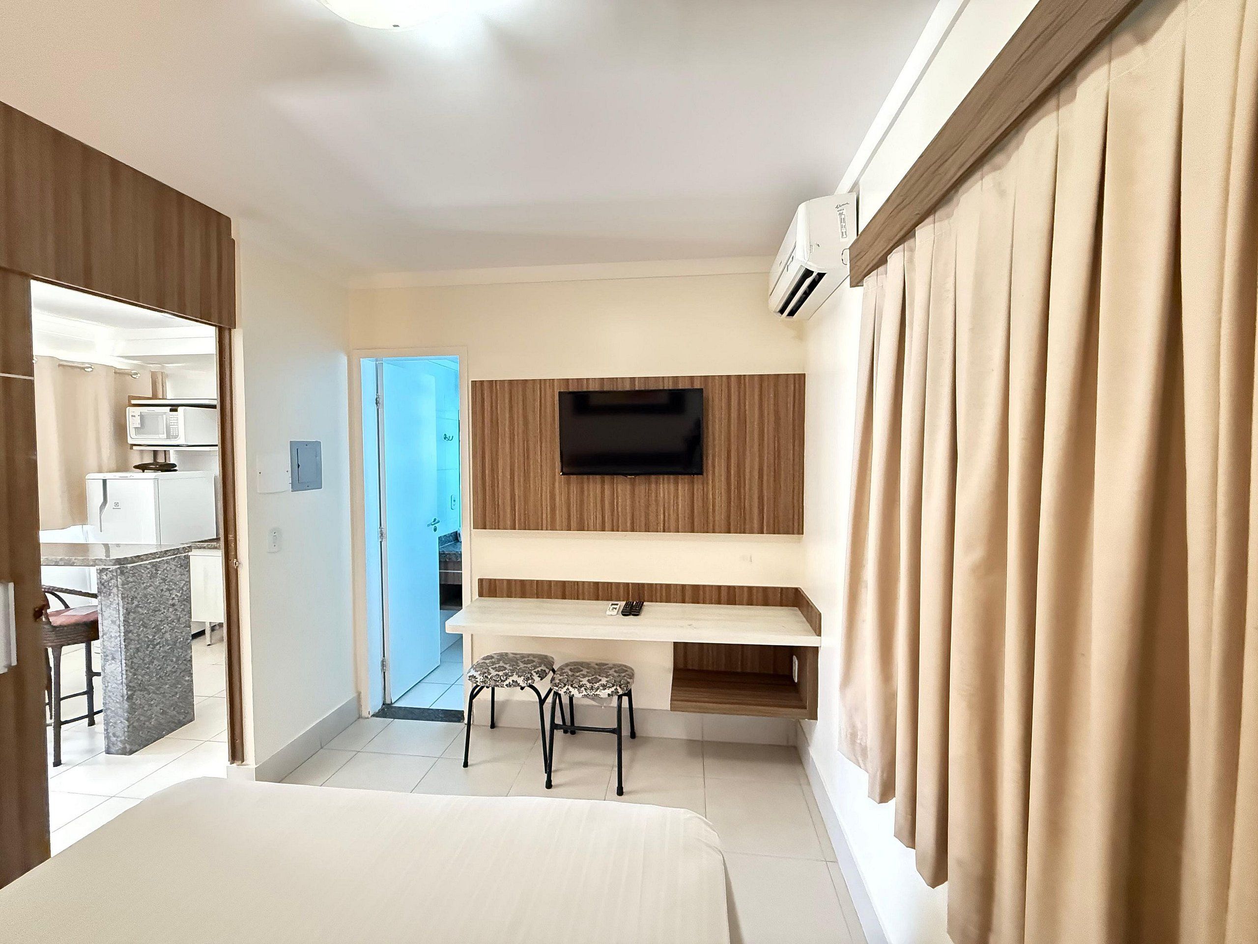 Ein Hotelzimmer mit Bett, Schreibtisch mit zwei Stühlen, Fernseher und Klimaanlage.