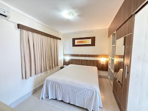 A hotel room with a bed, curtains, a wall-mounted light, a framed picture, and a wardrobe. - Lacqua Di Roma I Via Caldas (Caldas Novas)