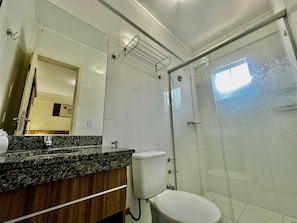 A bathroom with a granite countertop, a toilet, a glass shower enclosure, and a mirror. - Lacqua Di Roma I Via Caldas (Caldas Novas)