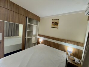 A hotel room with a bed, a wardrobe, a shelf unit, a wall-mounted light, and a poster. - Lacqua Di Roma I Via Caldas (Caldas Novas)