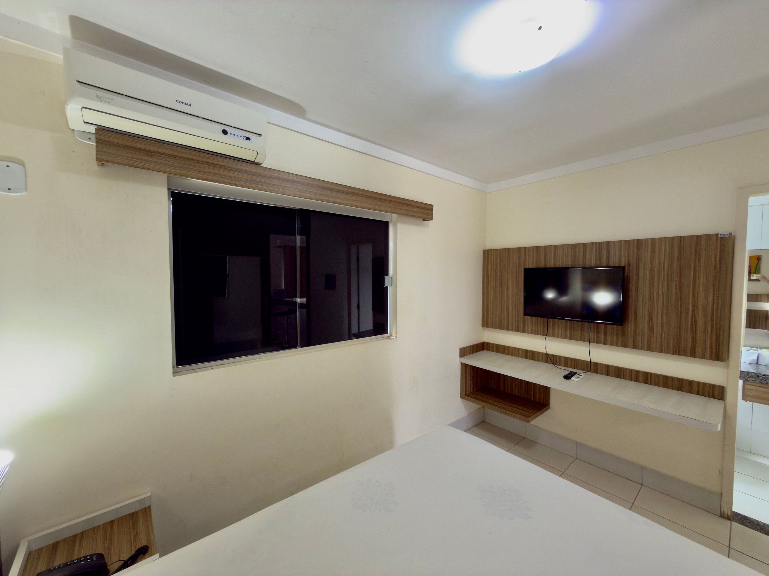 A room with a large window, a mounted TV, and a built-in air conditioning unit.