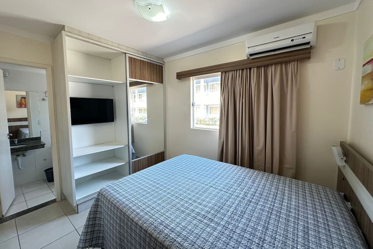 Une chambre à coucher comprenant un lit, une télévision, une armoire et un appareil de climatisation.