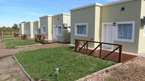 Una hilera de casas móviles de un solo piso y color claro, con ventanas pequeñas y techo plano. Cada unidad tiene un pequeño porche con un banco de madera.