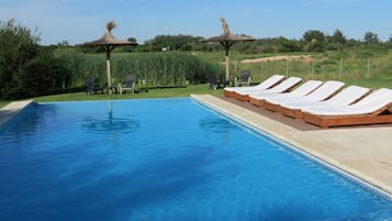 Una piscina al aire libre, sillones reclinables de piscina