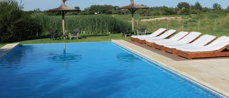 Una piscina al aire libre, sillones reclinables de piscina