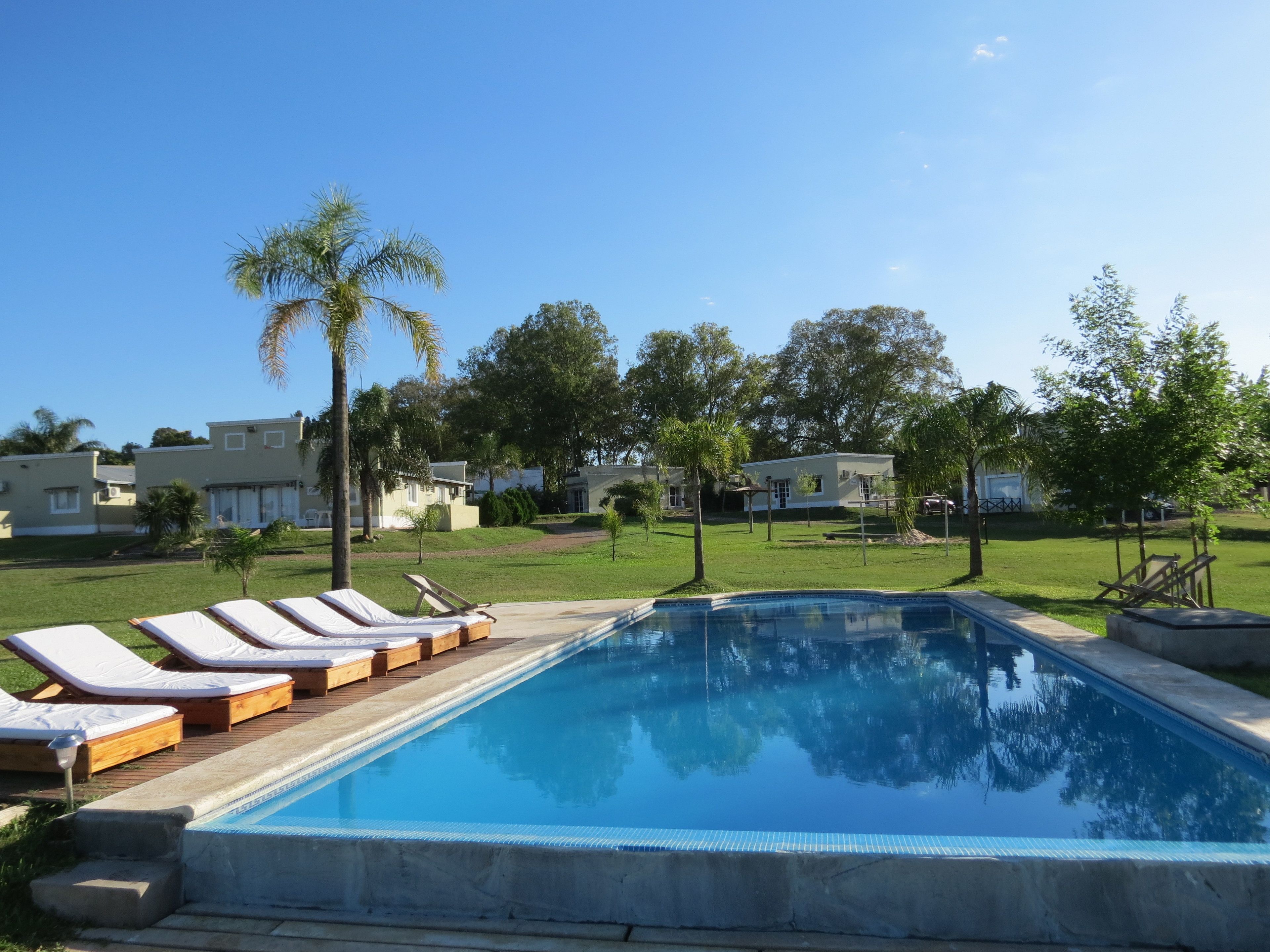 A swimming pool with lounge chairs and a clear sky.