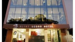 Un hotel moderno con fachada de vidrio, entrada visible y un letrero que indica que es un hotel urbano.