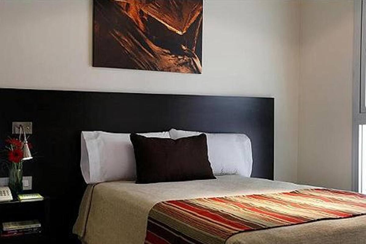 Ein Schlafzimmer mit einem Bett, einem Nachttisch, einer Lampe und einem Bild an der Wand.