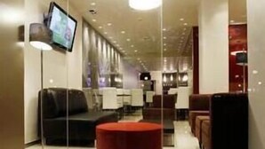 Un interior moderno con un separador de vidrio, un reposapiés rojo y un televisor de pantalla plana montado en la pared.