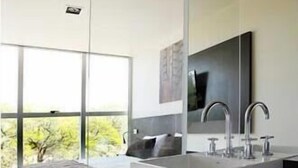 Un baño moderno con un espejo grande, dos lavamanos y vistas a zonas verdes.