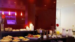 Mesa de buffet con diferentes alimentos, velas y una bodega de vinos al fondo.