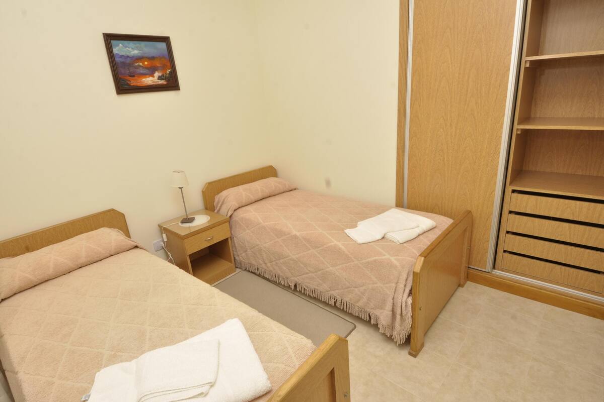 Une chambre avec deux lits, une table de chevet, une commode et une armoire.