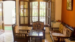 A hotel room with a bed, a table, two chairs, a sofa, and a window with shutters. - Hotel Bavaria (Asunción)