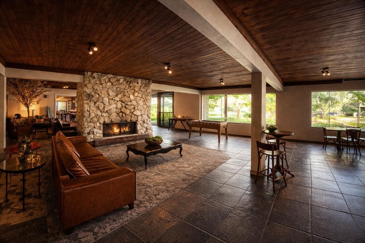 Un salón espacioso con chimenea de piedra, sofá de cuero y comedor con sillas de madera.