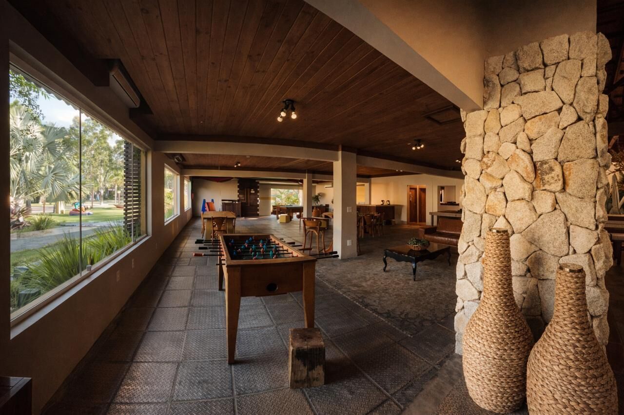 A spacious indoor area with a foosball table, stone wall, and large windows overlooking a garden.