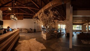 Eine geräumige Lobby mit einem Holzbüro, einem großen Baum und einer Steinwand.
