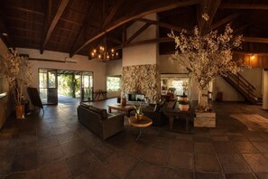 A spacious living area with a stone fireplace, comfortable seating, and large windows allowing natural light. - Hotel Acqua Lokos (Capao da Canoa)