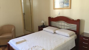A neatly made bed with white linens and towels, a wooden headboard, a bedside table with a lamp, and a painting on the wall. - Hotel de Conto (Porto Alegre)