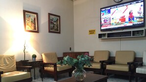 A living room with a television, two framed pictures, and a coffee table with a vase. - Hotel de Conto (Porto Alegre)