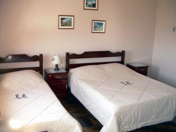 A hotel room with two single beds, a nightstand with a lamp, and a small table. - Hotel de Conto (Porto Alegre)