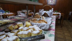 A buffet setup with various food items, including cakes and bread, arranged on tables with floral tablecloths. - Hotel de Conto (Porto Alegre)
