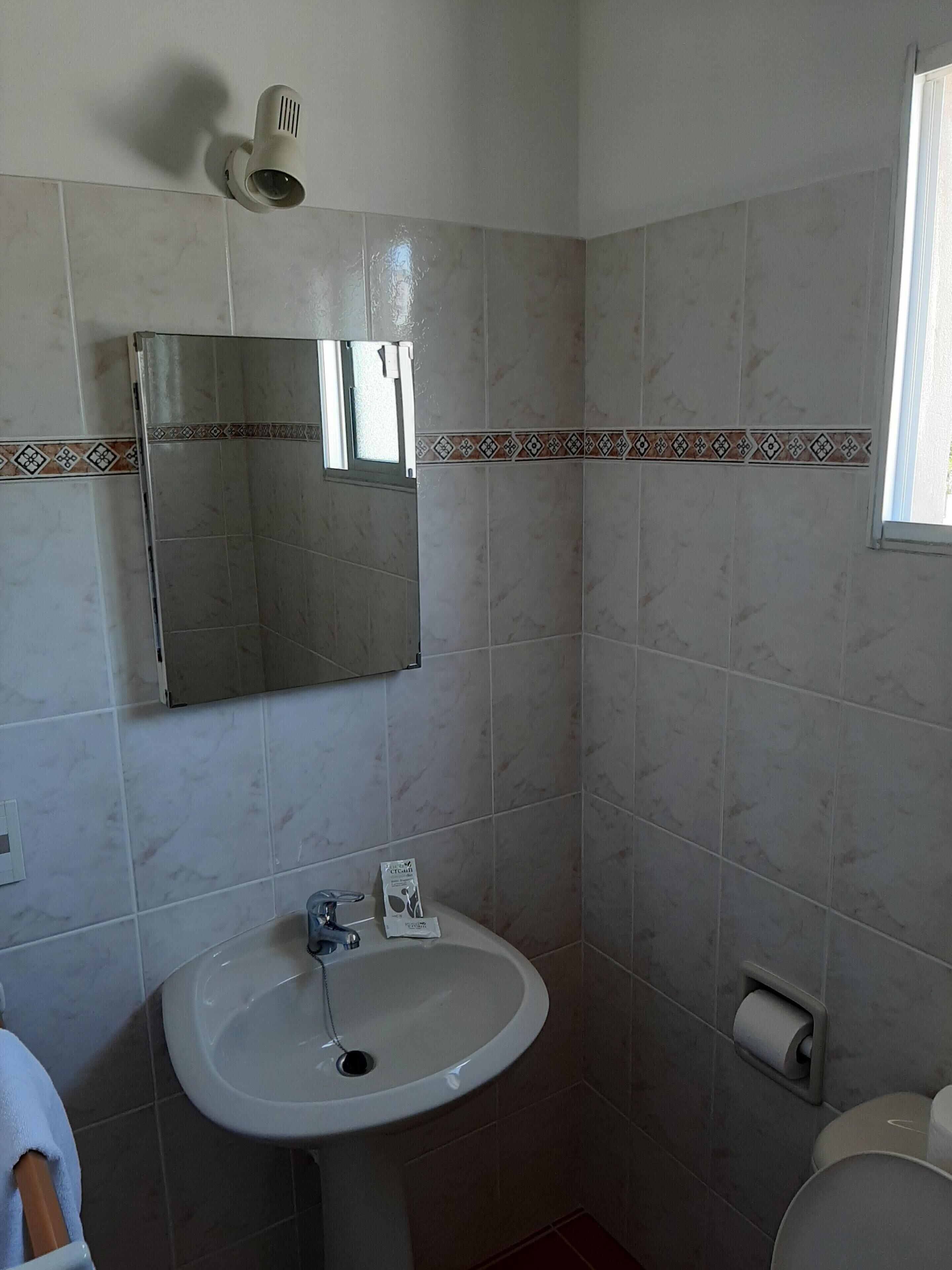 A bathroom with a white sink, a mirror, and a toilet.