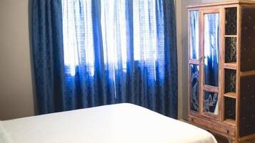 A bedroom with a bed, a wooden cabinet, and a window with blue curtains.