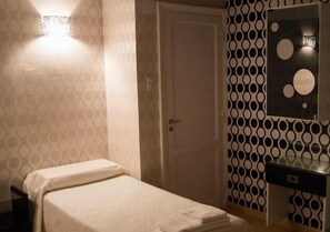 Une chambre d’hôtel avec un lit, une table de chevet, un miroir et un mur décoré d’un motif.