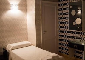 Una habitación de hotel con cama, mesita de noche, espejo y pared con diseño.