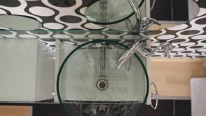 Un baño con un lavabo de vidrio y un techo moderno con diseño.