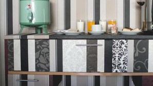 Una cocina con un dispensador de agua verde, una cafetera y alimentos para el desayuno sobre la encimera.