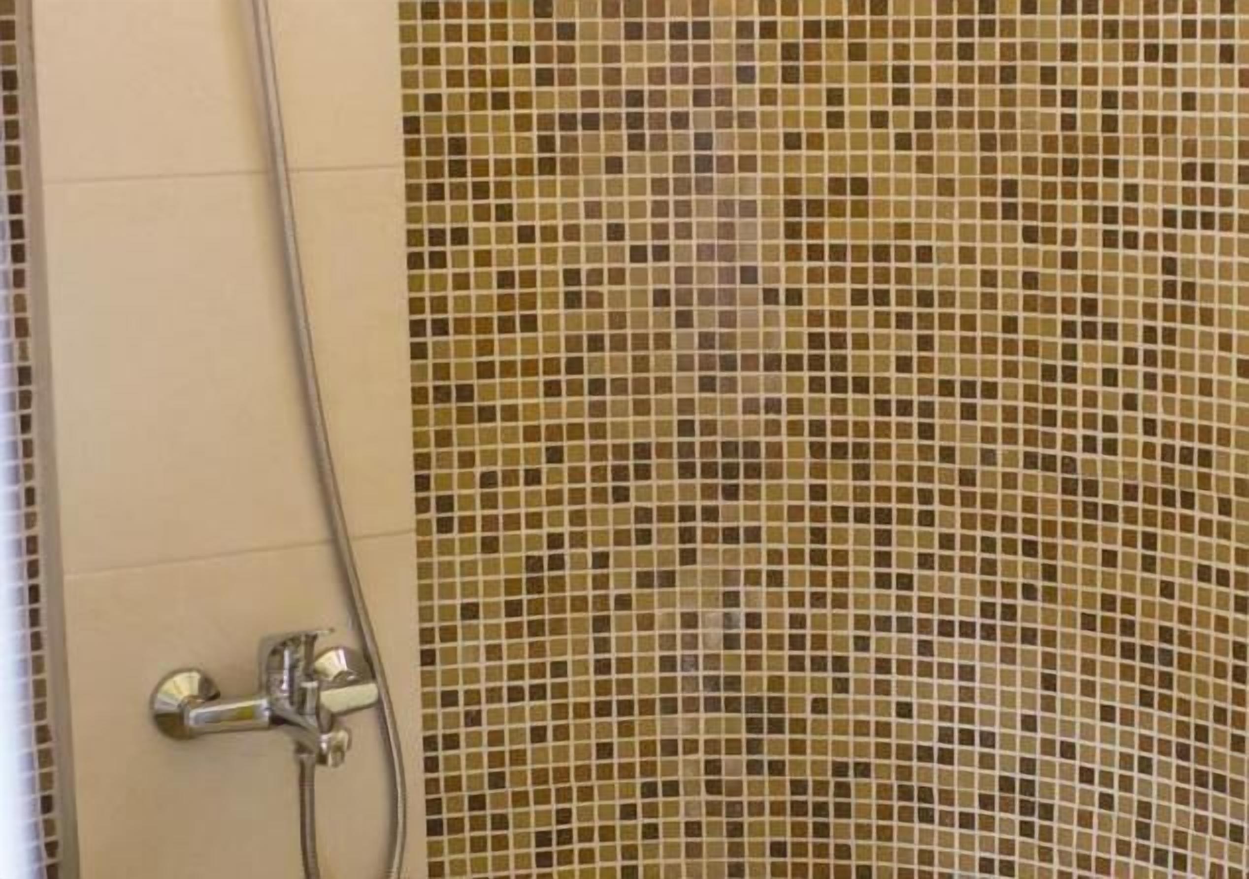 Zona de ducha con pared de azulejos y cabezal de ducha cromado.