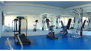 Un gimnasio con equipo de ejercicio, una cinta de correr y un espejo grande.