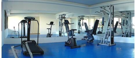 A gym with exercise equipment, a treadmill, and a mirrored wall.