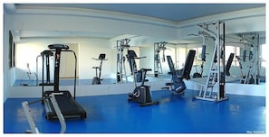 A gym with exercise equipment, a treadmill, and a mirrored wall. - Bouganville Hotel (Beberibe)