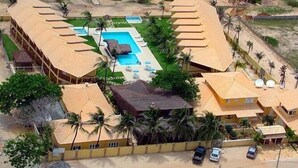 Un resort con piscina, playa y montañas al fondo.