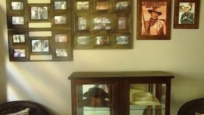 Una habitación con una pared de cuadros enmarcados y un mueble de madera con puertas de vidrio.