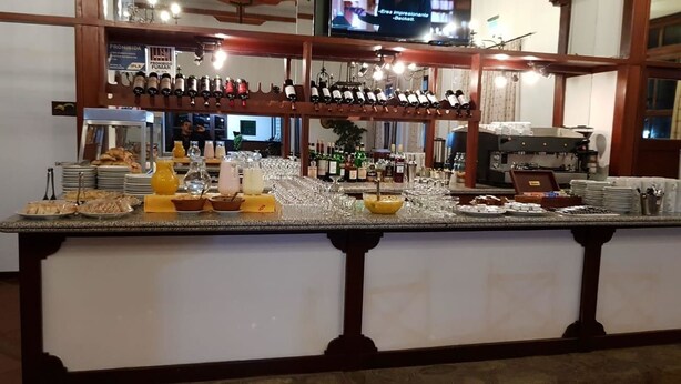 A breakfast bar with various food items and beverages, a coffee machine, and a wine rack. - Hostería ACA Tafí del Valle (Tafi del Valle)
