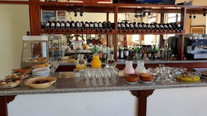 A bar area with wine bottles, glasses, and various food items. - Hostería ACA Tafí del Valle (Tafi del Valle)