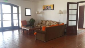 A lobby with a sofa, chairs, a table, a potted plant, and a painting on the wall. - Hostería ACA Tafí del Valle (Tafi del Valle)