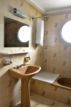 A bathroom with a beige sink, a mirror, a towel rack, and a bathtub. - Hotel El Velero (Villa Gesell)