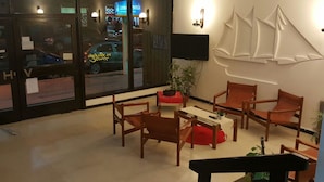 Un hall de hotel con mobiliario de madera, un televisor de pantalla plana y grandes ventanales con vistas a la ciudad.
